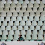A cricket supporter sits alone in the stands during the first Test between South Africa and Australia in Durban